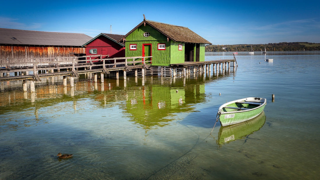 Bunte Bootshäuser und ein kleines gruenes Boot. Die bunten Bootshäuser sind definitiv eine der Sehenswürdigkeiten am Ammersee