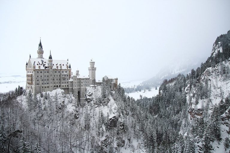 Schloss Neuschwanstein leicht mit Schnee bedeckt. Die umgebende Landschaft ist auch leicht angeschneit.